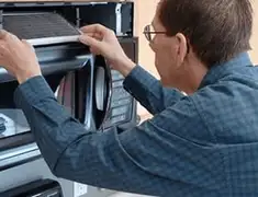 Appliance repair technician replacing a microwave vent filter in Springfield, MO