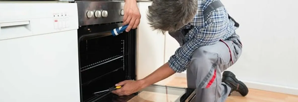 Oven repair technician inspecting and servicing an electric oven in Springfield, MO
