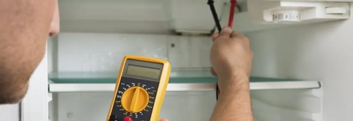 Refrigerator repair technician testing electrical components with a multimeter in Springfield, MO