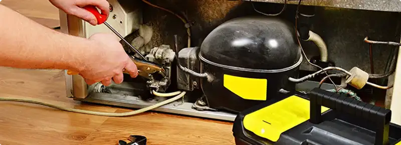 Refrigerator repair technician fixing the compressor and wiring in Springfield, MO
